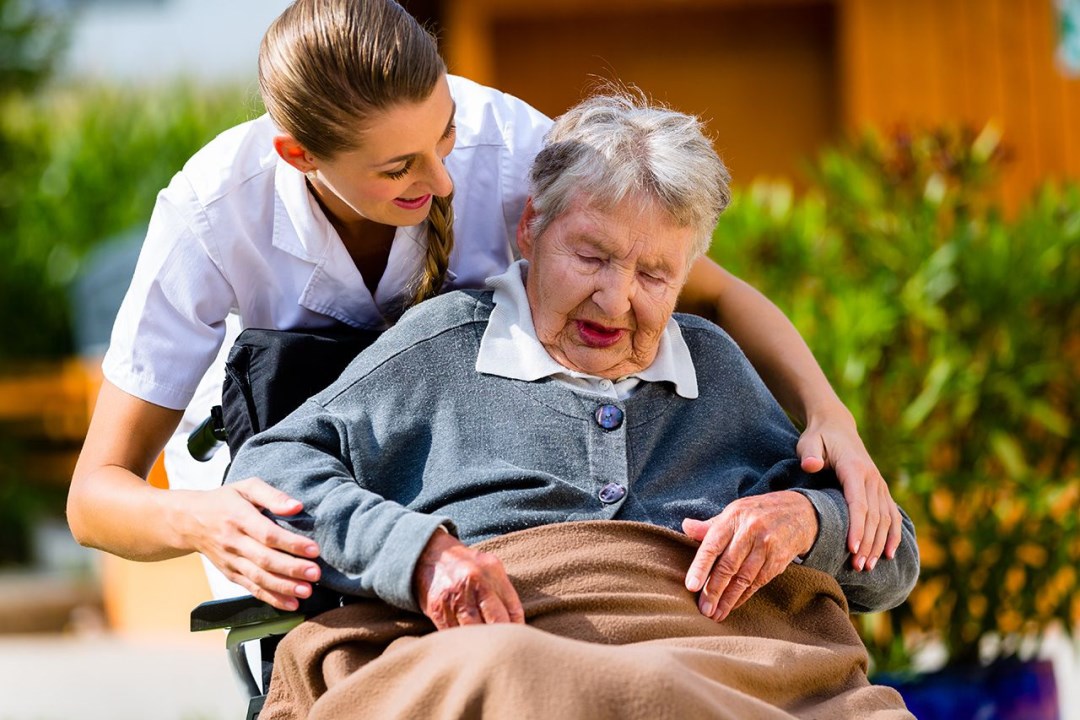 senior-woman-in-nursing-home-with-nurse-in-garden (1)